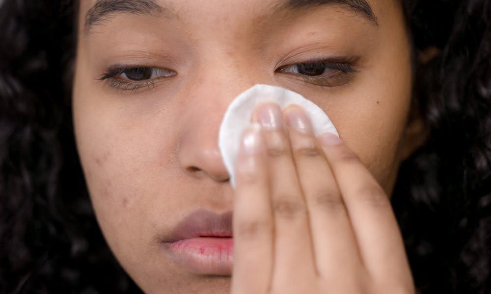 Close-up of a woman using a cotton pad for skincare, focusing on self-care and hygiene. .pexels