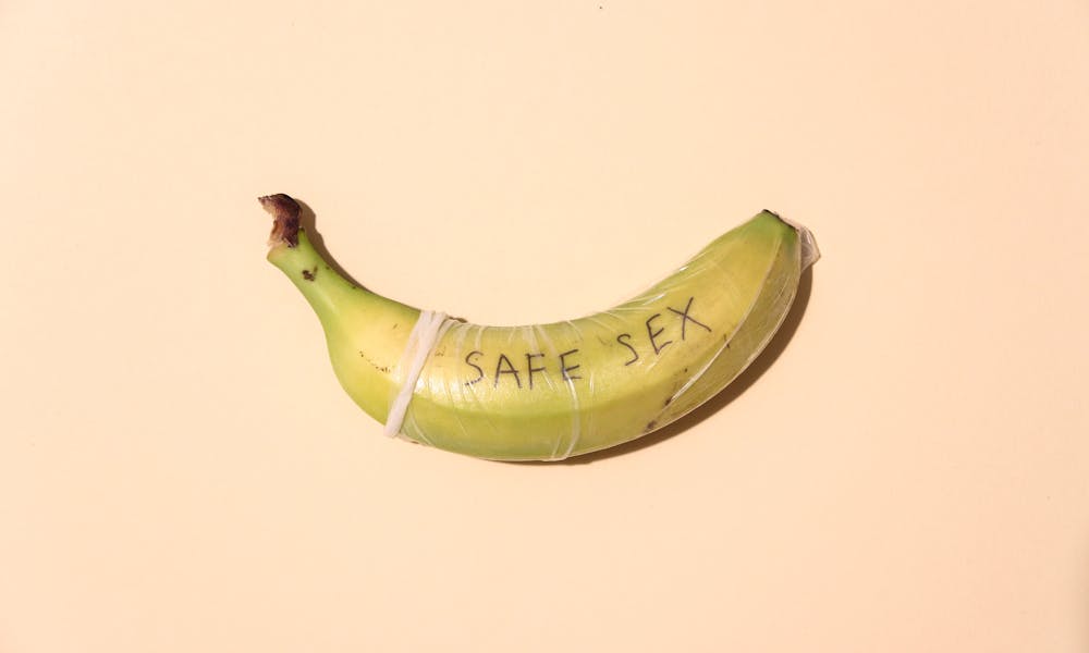 A banana wrapped in a condom for safe sex awareness on a pastel background. .pexels