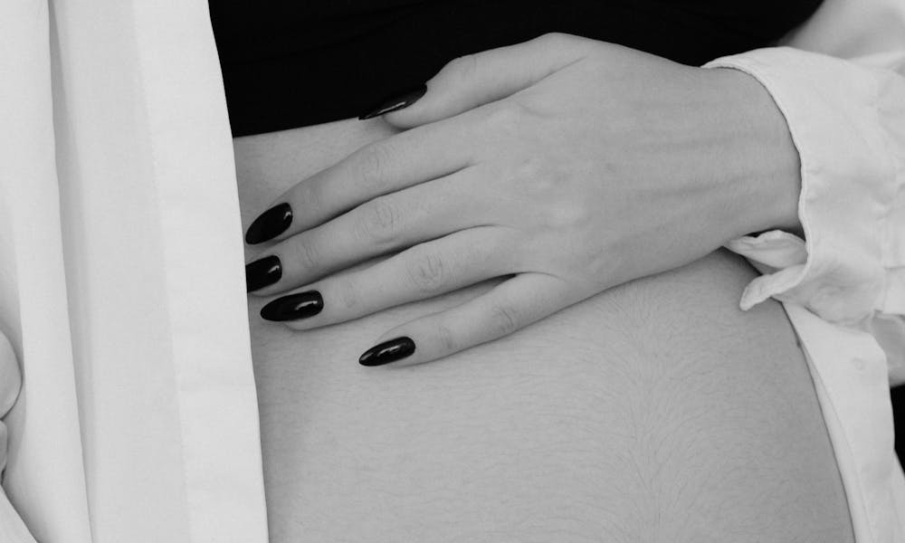 Black and white image of a pregnant woman gently holding her belly. .pexels