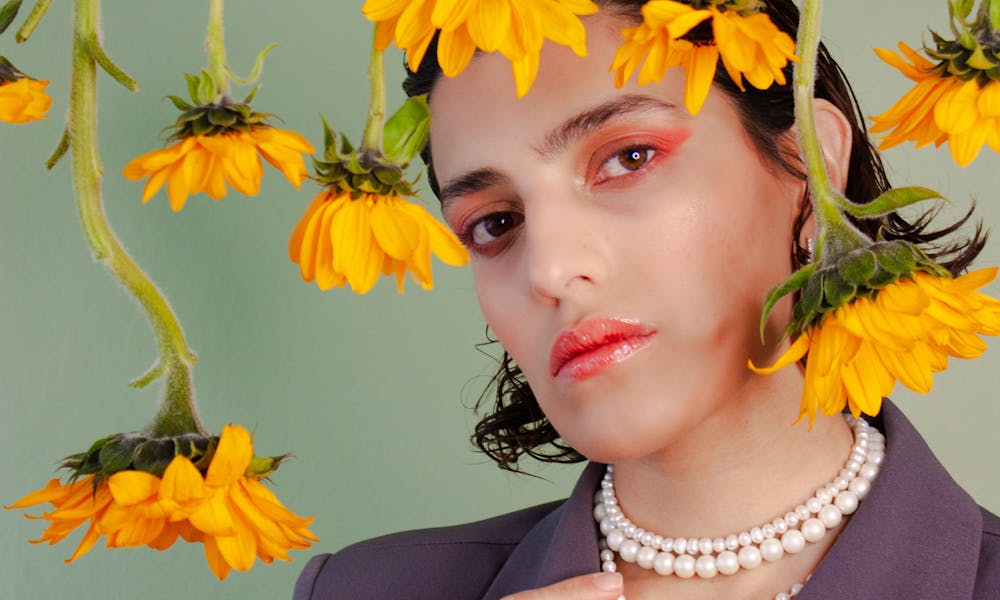 Stylish portrait of a person surrounded by hanging sunflowers in a unique artistic setup. .pexels