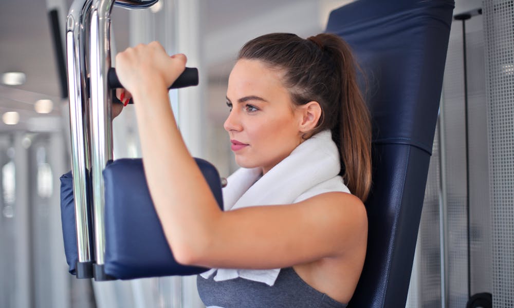 Young woman working out on a chest press machine in the gym, showing strength and determination. .pexels