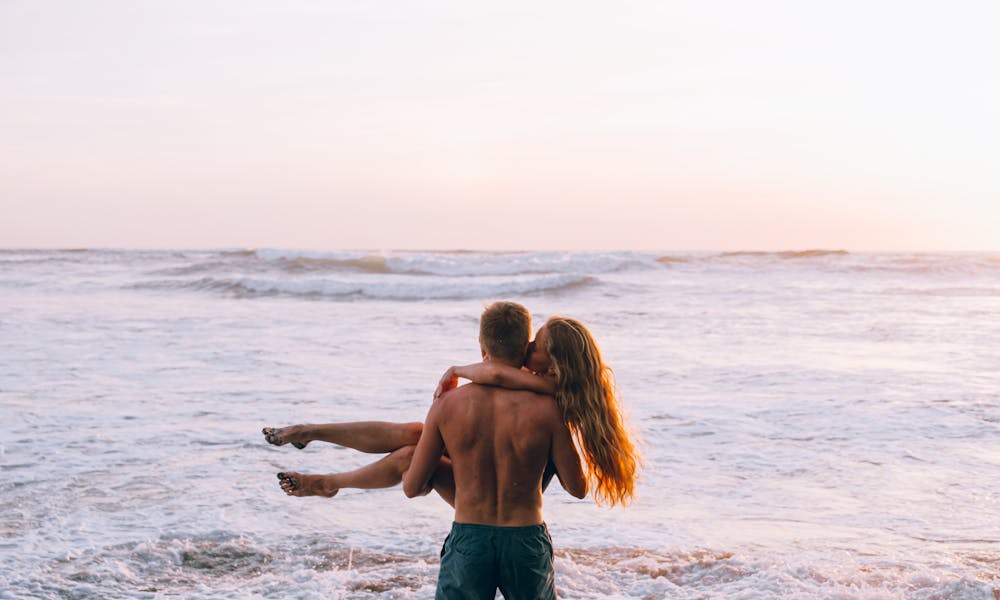 A couple in a loving embrace on a beach during sunset, symbolizing romance and tranquility. .pexels