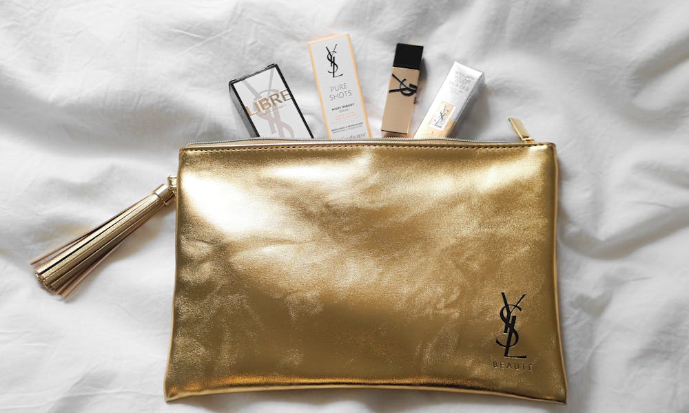 Luxurious YSL beauty products elegantly arranged on a golden pouch. .pexels