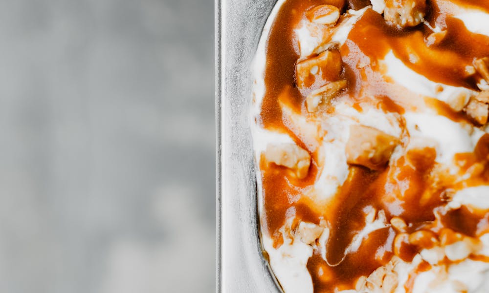 Close-up of creamy ice cream topped with rich caramel sauce and nuts, perfect for dessert lovers. .pexels