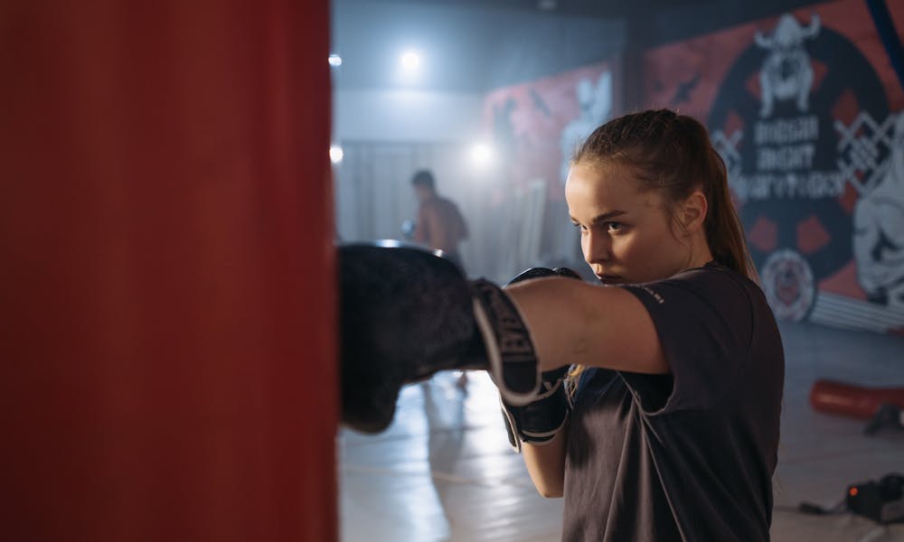 Young female boxer practicing punches with gloves in a gym. Intense training session. .pexels