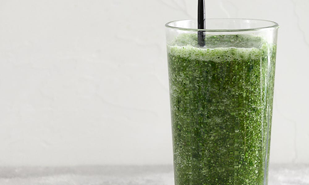 A healthy, refreshing green smoothie served in a tall glass with a black straw, against a minimalist background. .pexels