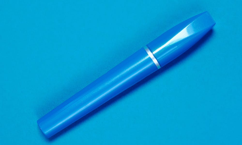 Close-up of a blue mascara tube set against a matching blue background, highlighting sleek design. .pexels