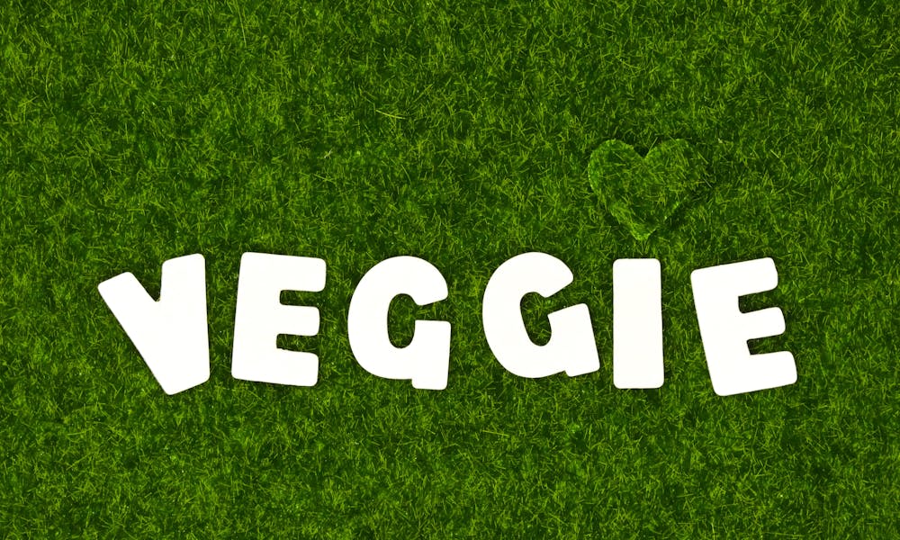 White block letters spelling 'veggie' on lush green grass with a heart shape, conveying a fresh and healthy lifestyle. .pexels