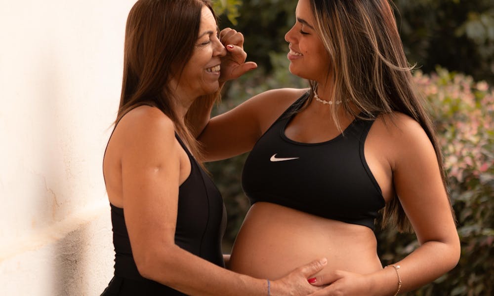 Pregnant woman sharing a joyful moment with her friend outdoors, radiating happiness and connection. .pexels