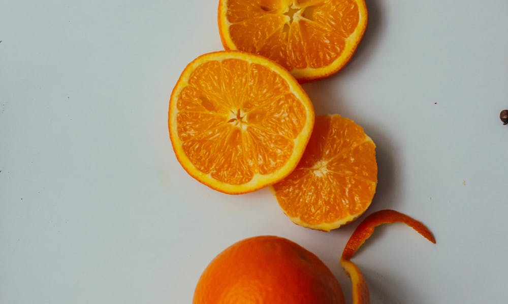 Sliced oranges and whole fruit artistically arranged in a white mug. .pexels