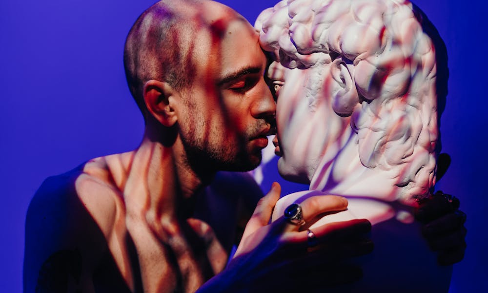 A man intimately engages with a sculpture, exploring themes of self-love and connection. .pexels