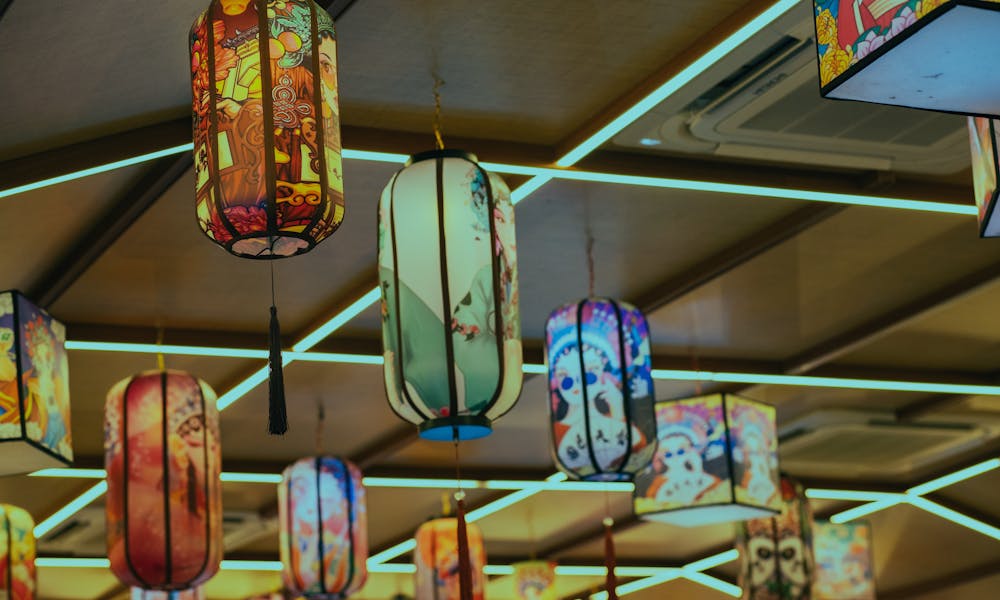 Colorful traditional lanterns hang from a ceiling creating a warm ambiance. .pexels