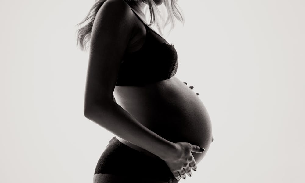 Silhouette of a pregnant woman in lingerie, expressing motherhood and contemplation. .pexels