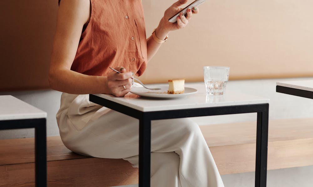 A young woman enjoys a quiet moment at a coffee shop, checking her phone while seated. .pexels