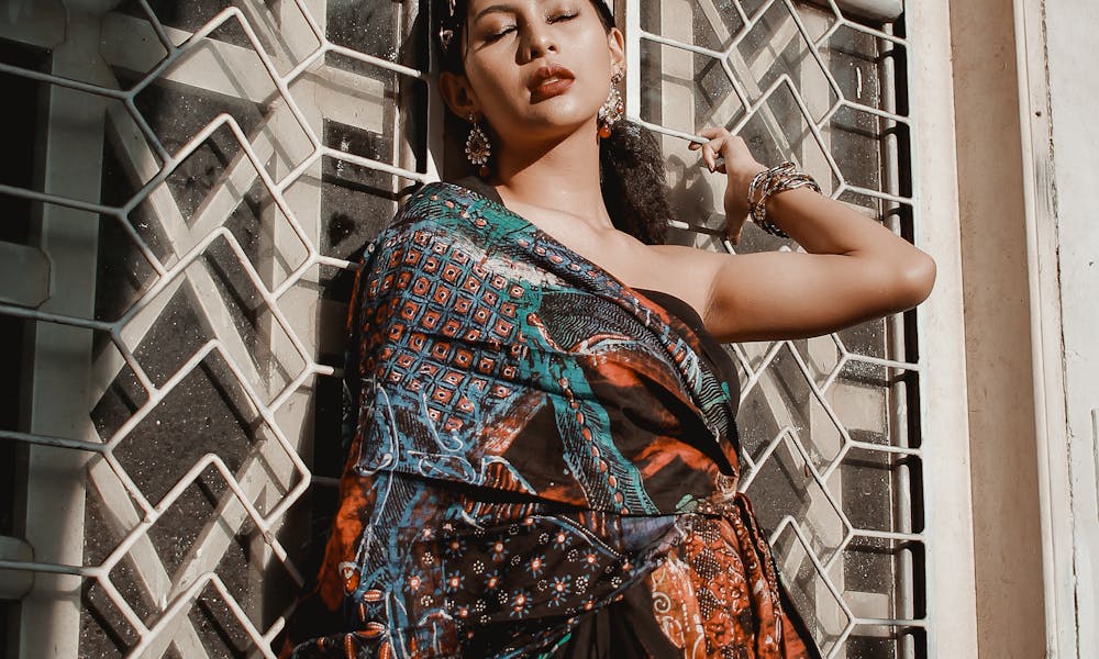 A fashionable woman poses elegantly in a colorful dress against a vintage window in Surabaya, Indonesia. .pexels