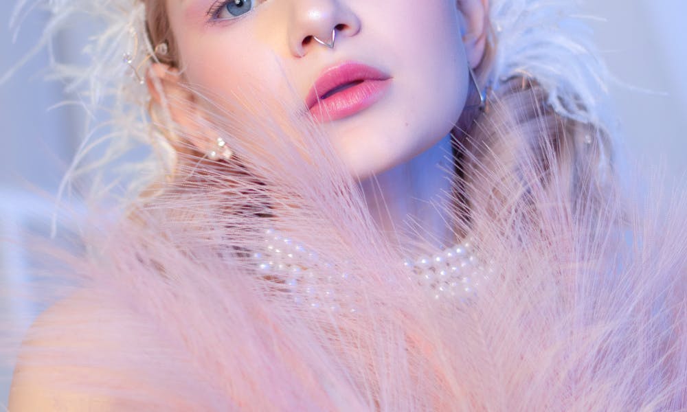 Elegant portrait of a woman adorned with pink feathers and pearls, showcasing dreamy beauty. .pexels