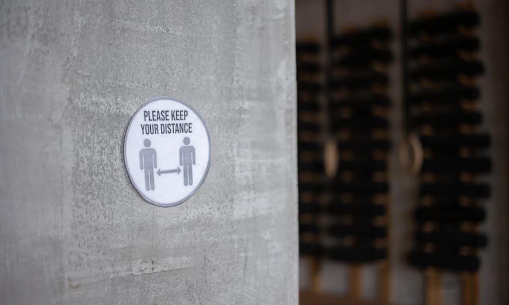 Concrete wall with 'Please Keep Your Distance' sign in an indoor gym. .pexels