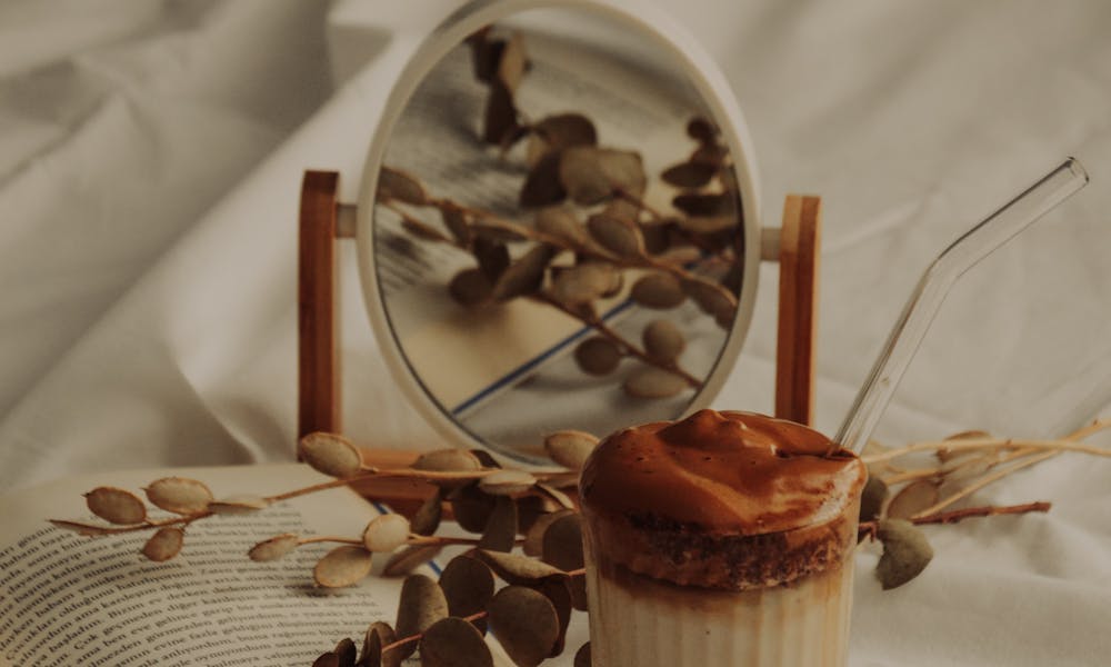 Warm autumn setup with a dalgona coffee, open book, and dried eucalyptus on a soft fabric background. .pexels