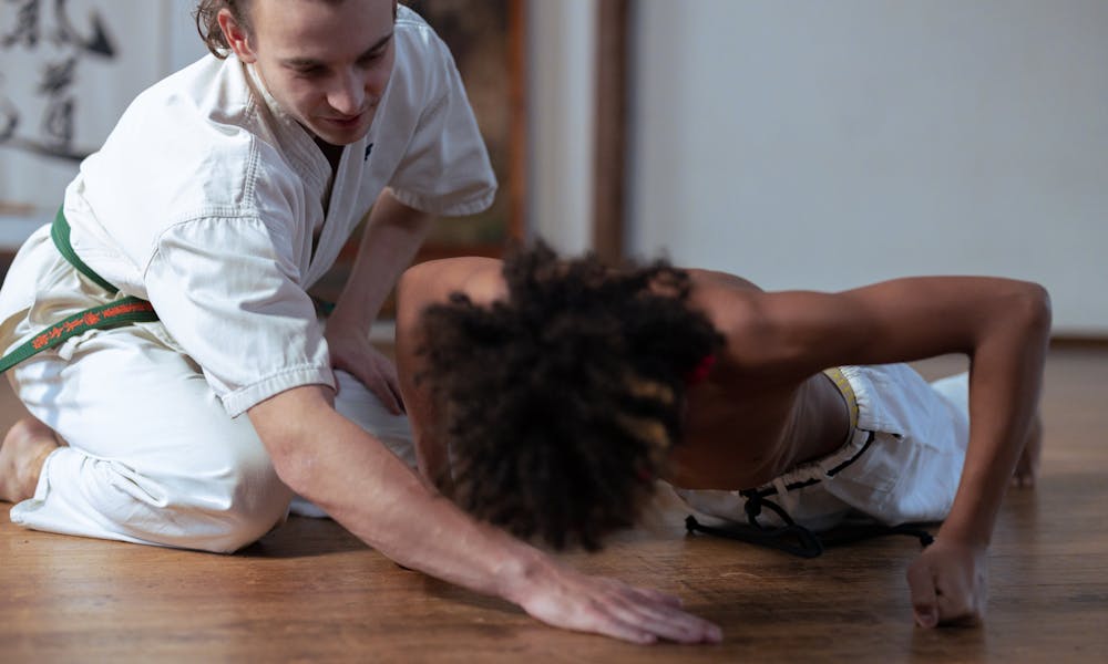 Karate trainer aids student during training session, showcasing martial arts practice and discipline. .pexels