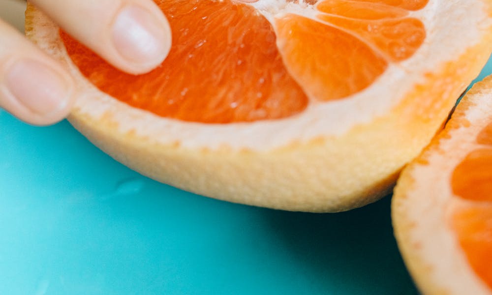 Artistic shot of a hand touching grapefruit, symbolizing sensuality. .pexels