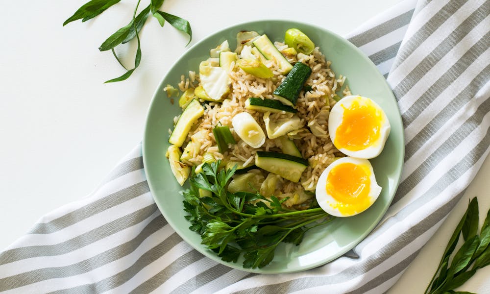 Delicious rice meal with zucchini, greens, and soft-boiled egg, perfect for a healthy diet. .pexels