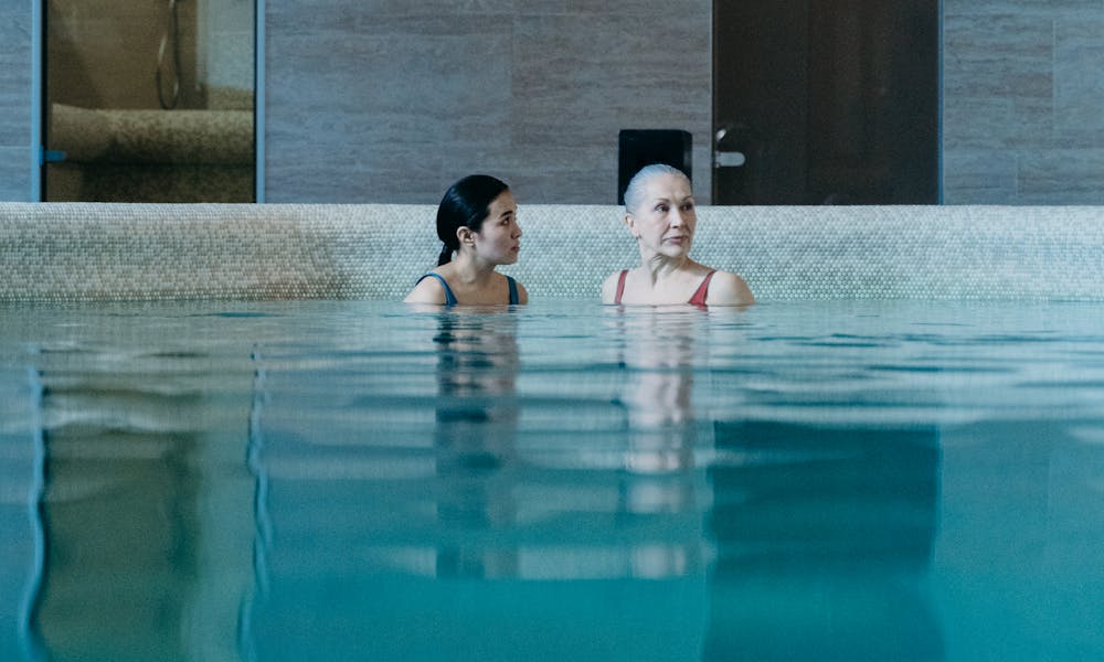 Two women relaxing in a serene indoor swimming pool, enjoying a peaceful moment together. .pexels