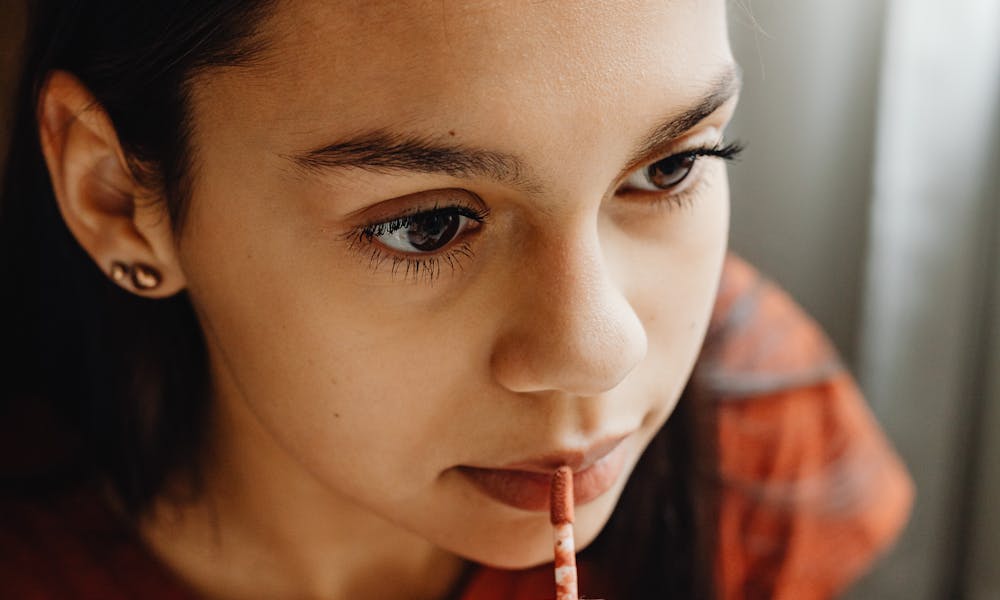 Close-up of a woman applying lip tint indoors, showcasing beauty and makeup application. .pexels