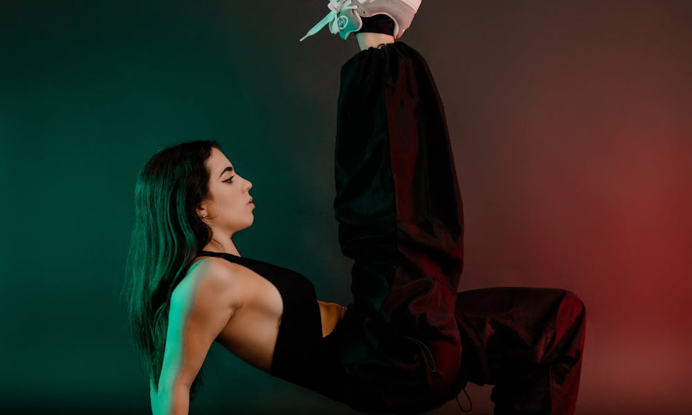 Woman in athletic wear performing a yoga pose with colorful studio lighting. .pexels