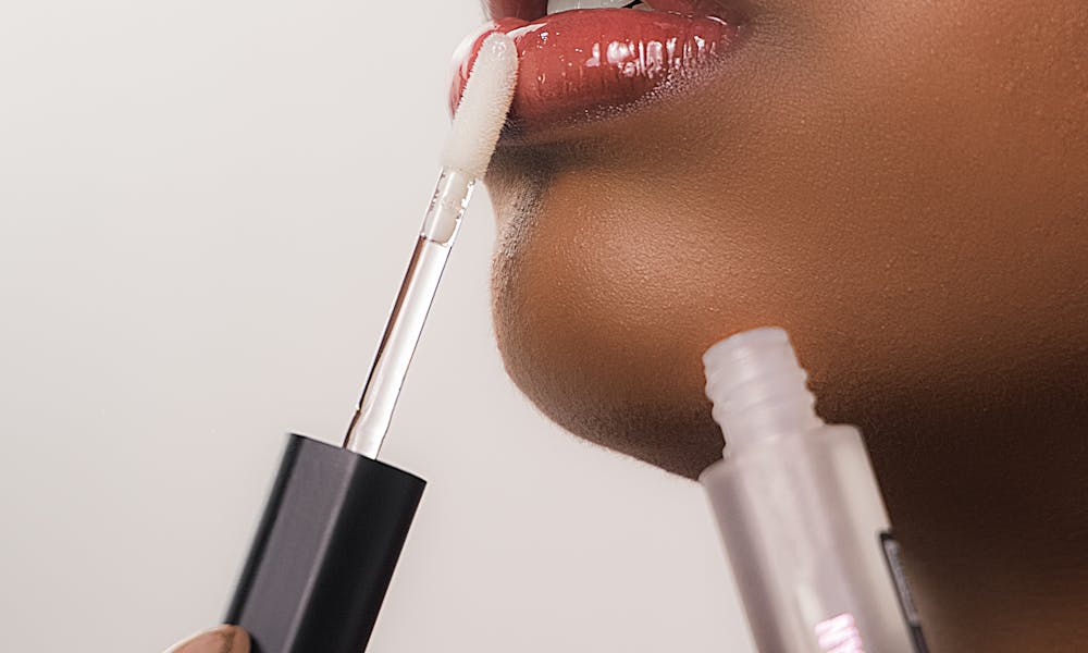 Detailed close-up of a black woman applying lip gloss, showcasing beauty and self-care. .pexels