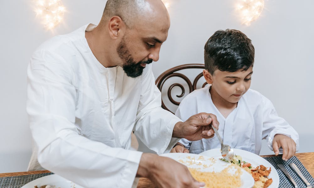 Father and son enjoying a home-cooked meal together indoors, sharing quality family time. .pexels