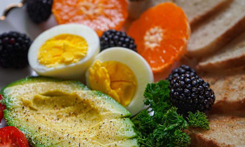 Vibrant breakfast plate with fresh avocado, eggs, and assorted fruits. .pexels