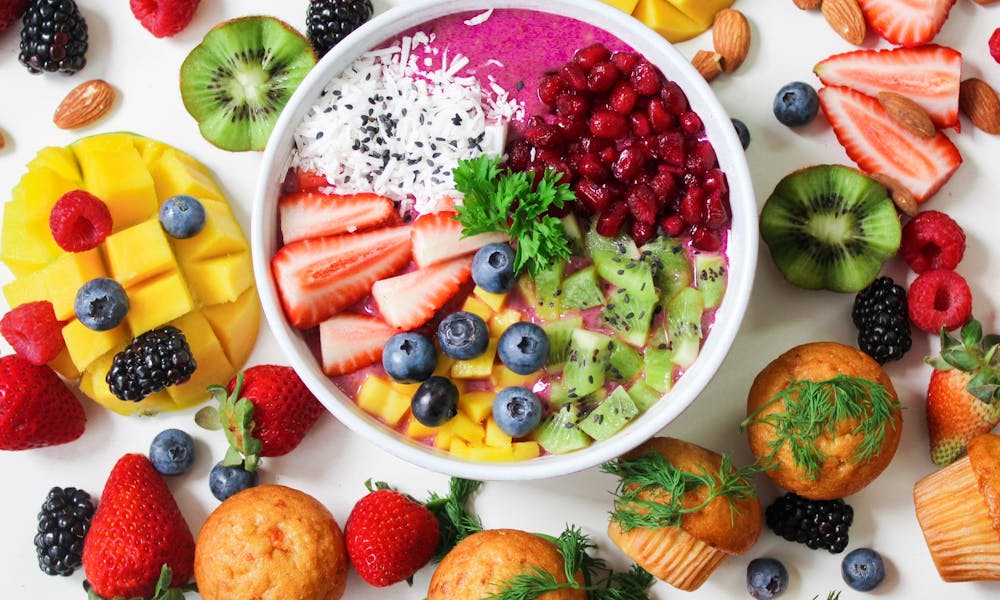 Vibrant smoothie bowl topped with assorted fresh fruits and muffins, perfect for a healthy snack. .pexels