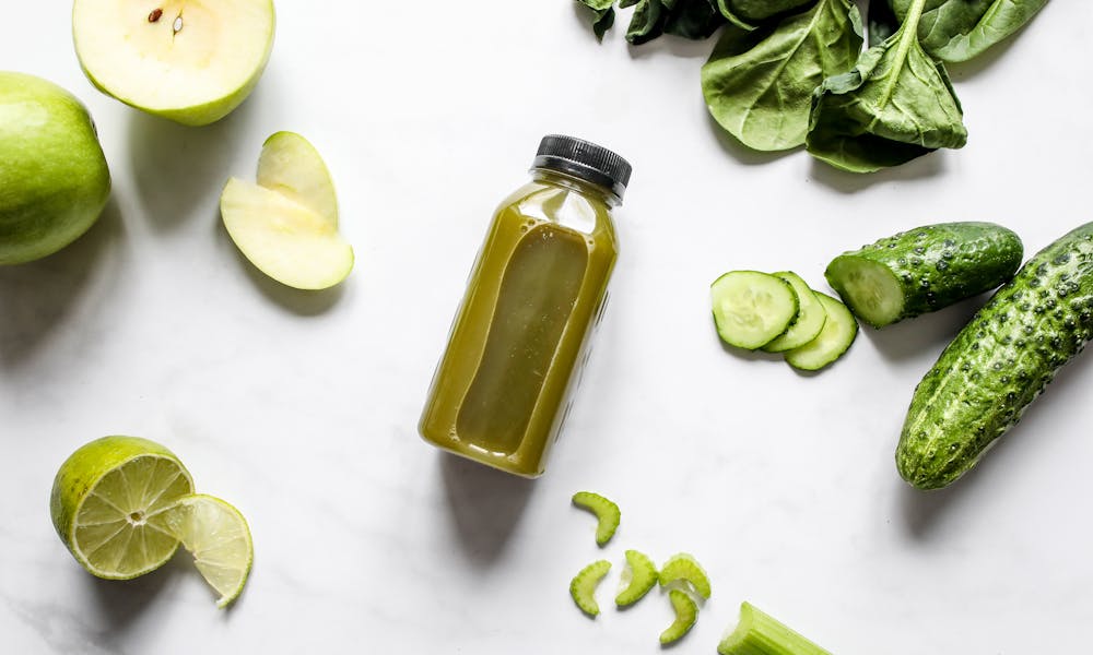 Discover fresh green juice surrounded by spinach, cucumber, apple, and lime. .pexels