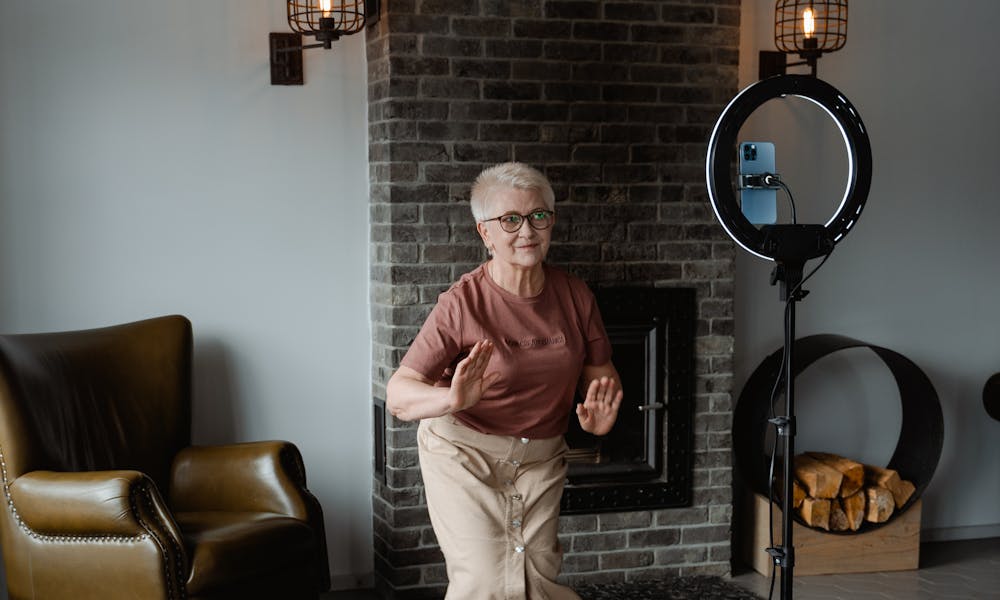 Elderly woman joyfully dancing in a cozy living room with a modern setup. .pexels