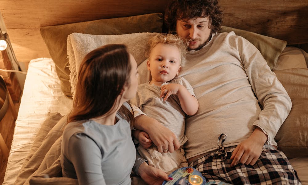 A peaceful family moment with parents and child relaxing in bed, embracing love and togetherness. .pexels