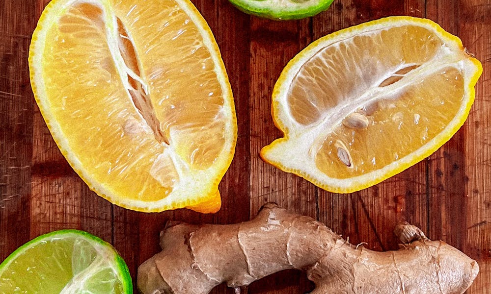 A colorful display of sliced citrus fruits and ginger root on a rustic wooden surface. .pexels