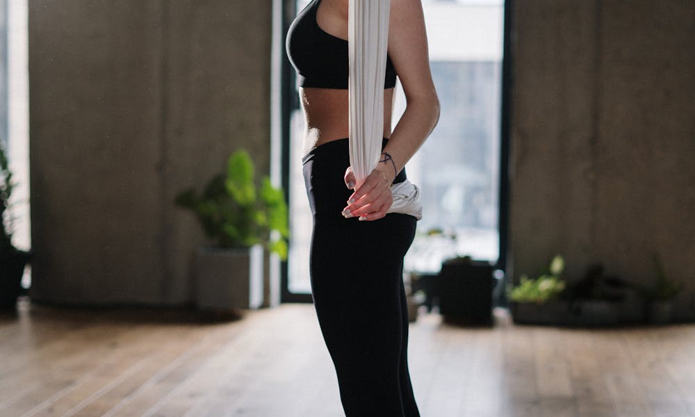 A woman engages in aerial yoga indoors, highlighting balance and fitness. .pexels