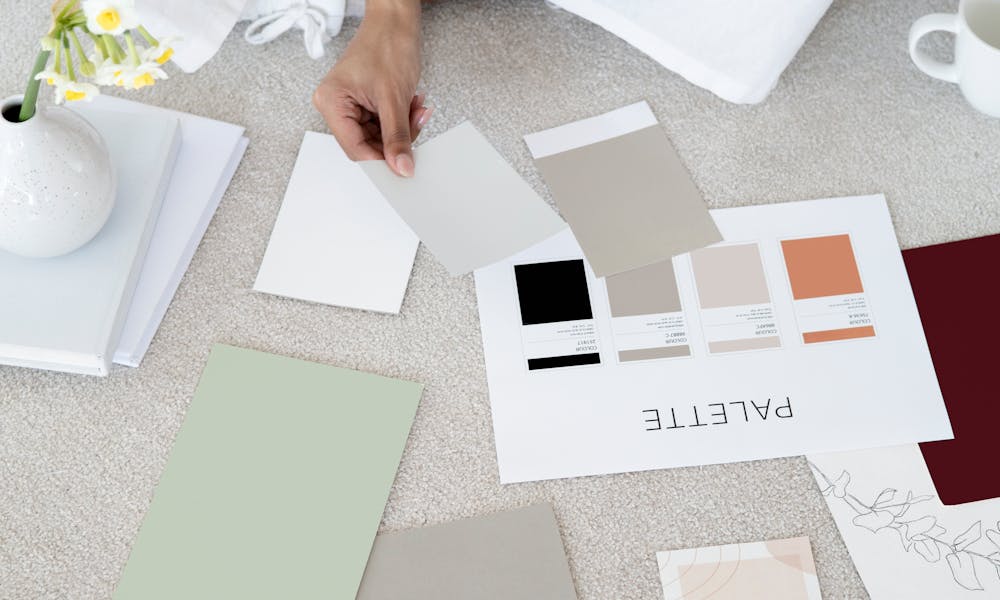 Designer sits on carpet with color palettes and samples, planning creative project. .pexels