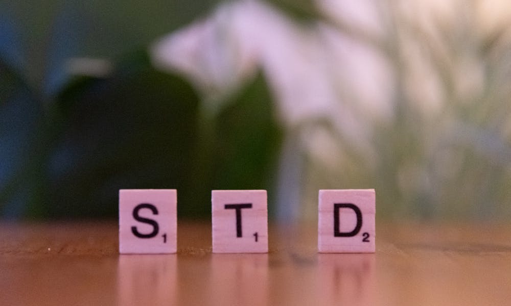 Scrabble tiles spelling 'STD' symbolize sexually transmitted diseases awareness and prevention. .pexels