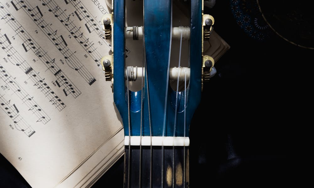 Guitar neck with vintage sheet music, creating a moody, musical ambiance. .pexels