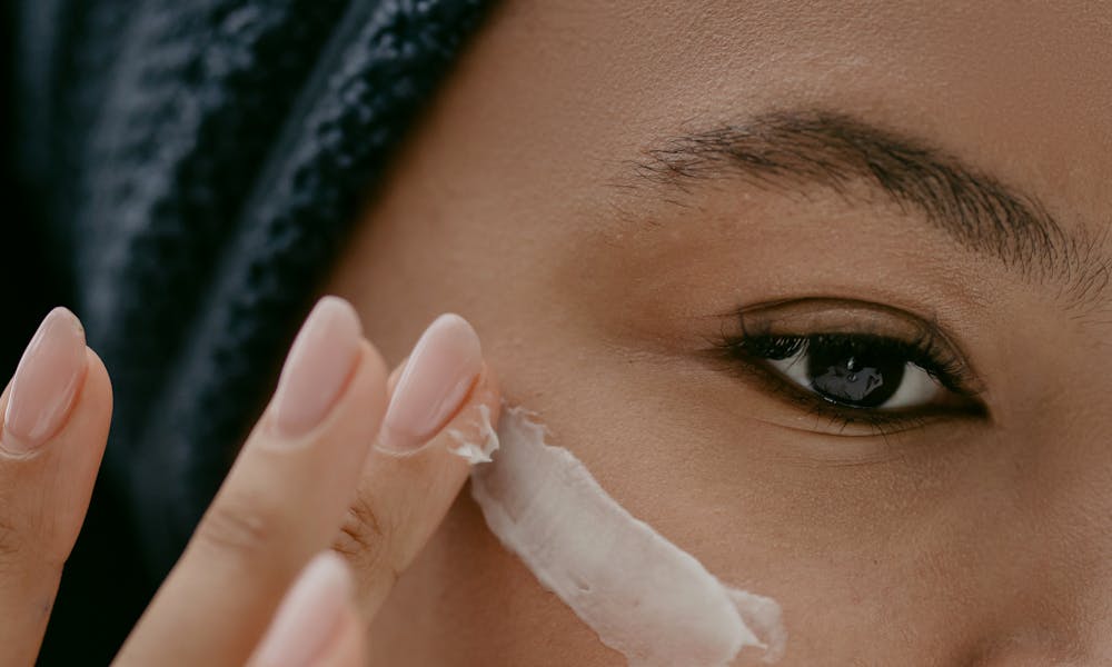 Extreme close-up of a woman applying cream to her cheek for healthy skin care. .pexels