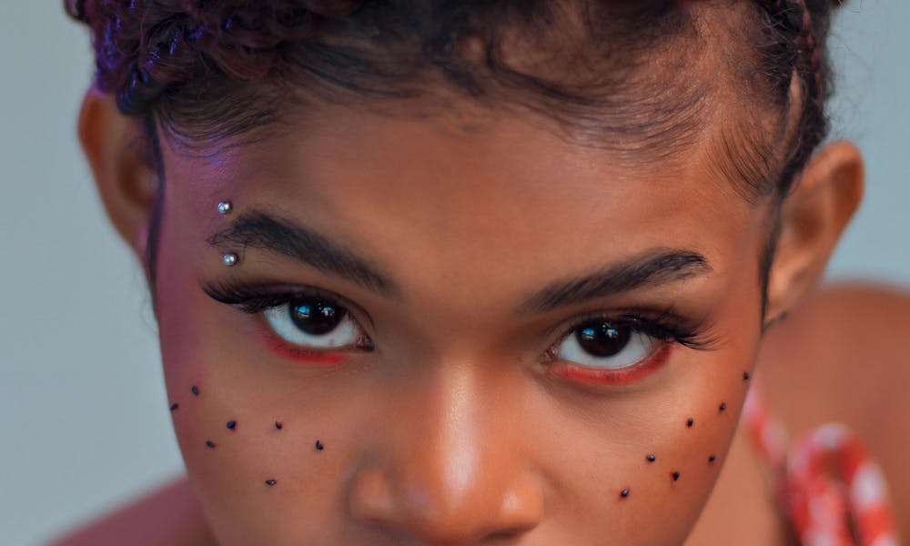 Close-up of a young woman with piercings holding a dragon fruit slice. .pexels