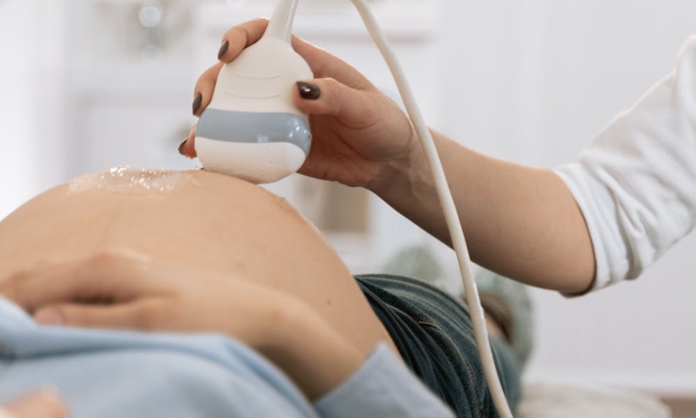 A pregnant woman undergoing a medical ultrasound in a clinical setting. .pexels