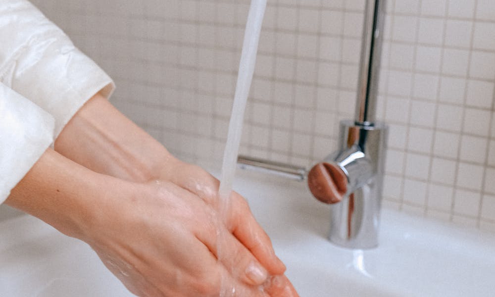 Close-up of a woman washing hands under a running faucet, promoting hygiene. .pexels