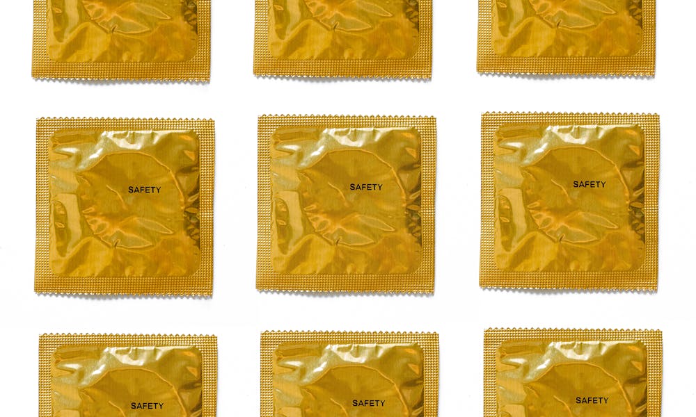 A collection of gold condom packages arranged on a white background for health and safety promotion. .pexels